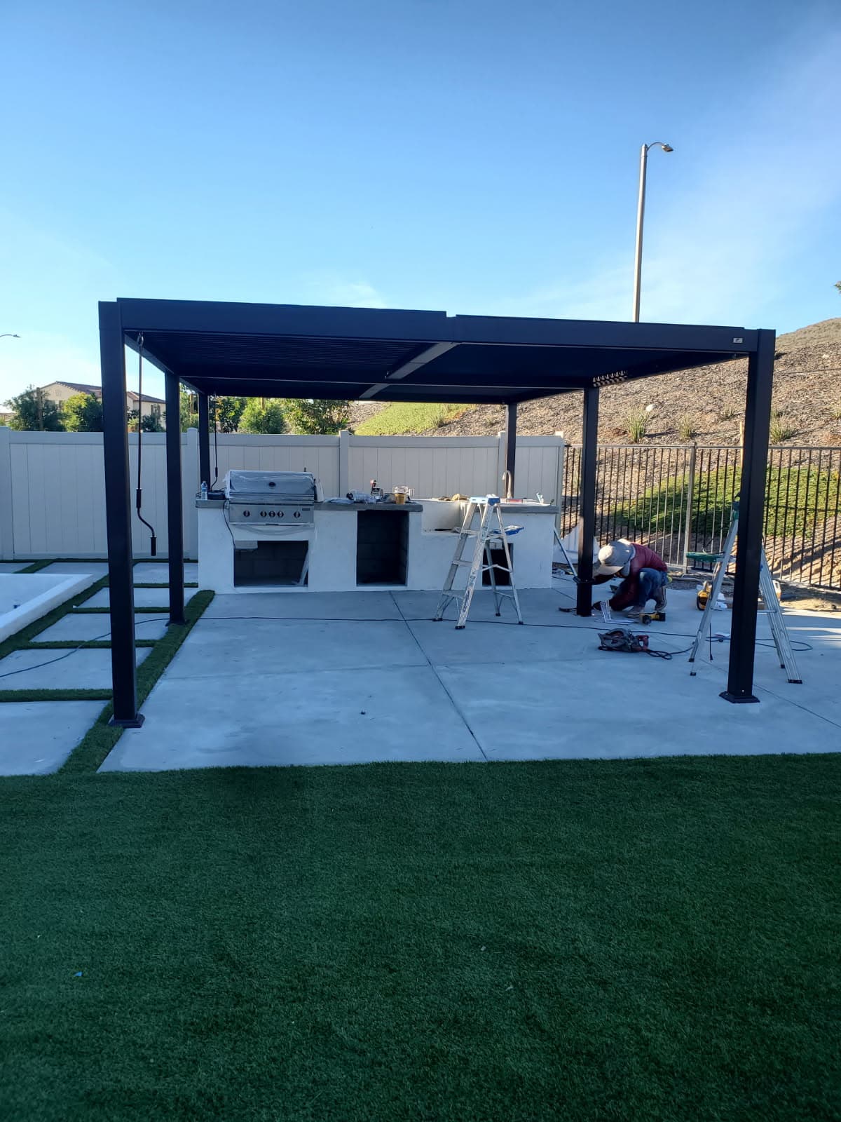Louvered aluminum pergola under construction over a concrete slab and outdoor kitchen, Palmdale CA