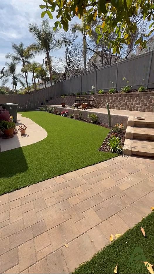 Backyard remodel with artificial turf, paver patio, and a retaining/seat wall