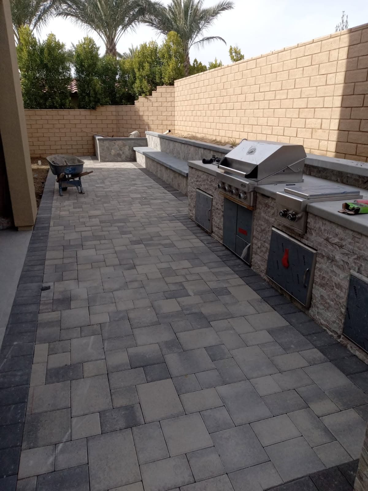 Stone-veneer BBQ island on a paver patio next to a block retaining wall