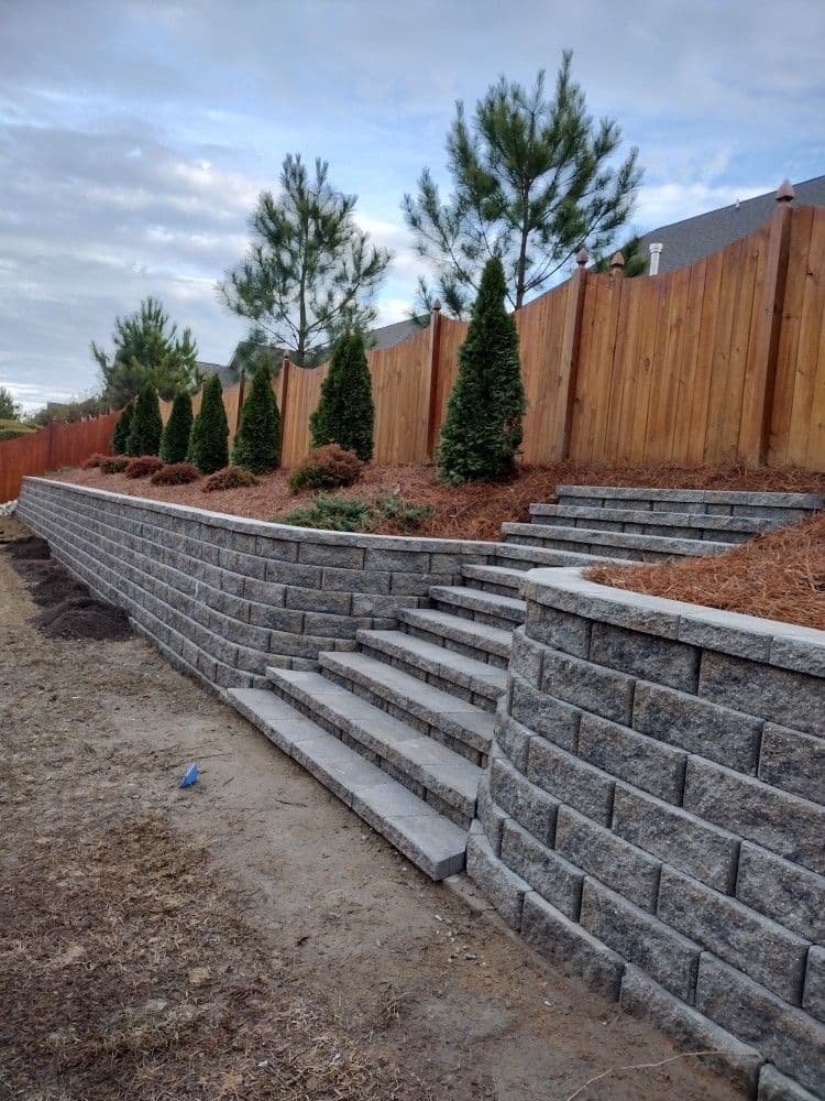 Segmental block retaining wall with built-in stairs along a sloped yard